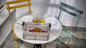 Disposição para o café da manhã com croissants, dois copos de suco de laranja e uma pequena cesta com a etiqueta 