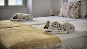 Quarto de hotel com duas camas, cada uma com toalhas bem dobradas e um frasco de loção.