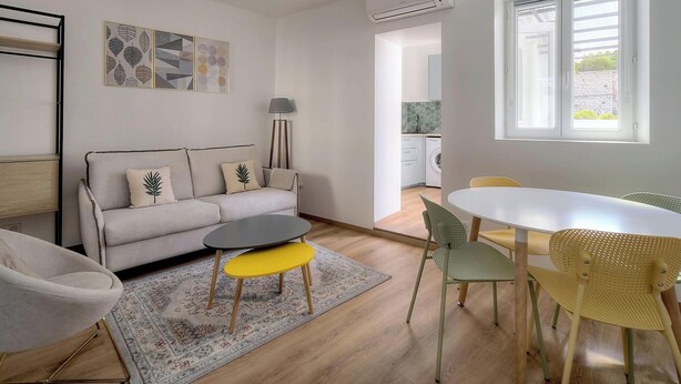 Uma sala de estar moderna com sofá, poltrona, mesa de centro e área de jantar.