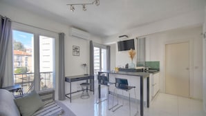 Un apartamento moderno con sala de estar, comedor y cocina. Cuenta con un ventanal grande, un televisor de pantalla plana y un balcón.