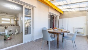 A modern kitchen with a dining area, featuring a wooden table, grey chairs, and a glass door leading to an outdoor space. - Ref 685546 in Cannes (Cannes)