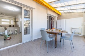 Eine moderne Küche mit Essbereich, ausgestattet mit einem Holztisch, grauen Stühlen und einer Glastür, die zu einem Außenbereich führt.