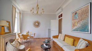 A spacious living room with a wicker sofa, a dining table, and a chandelier. - Lumineux 3 Pieces Dans LE Carre D OR A2b196 (Cannes)