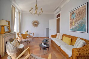 Ein geräumiges Wohnzimmer mit einem Korbssessel, einem Esstisch und einer Chandelier.