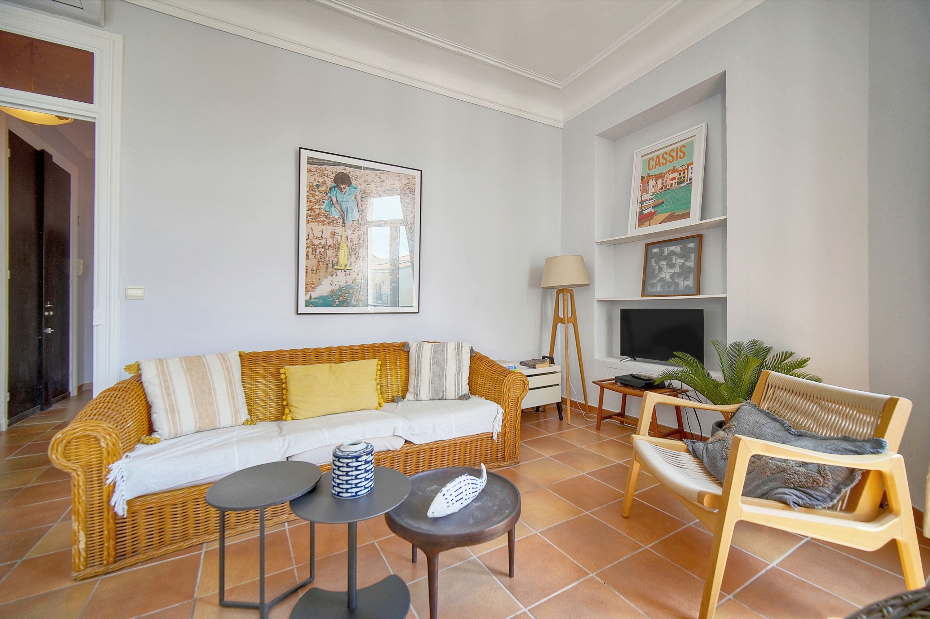 Un salon avec un canapé, une petite table, un fauteuil, une lampe et un téléviseur.