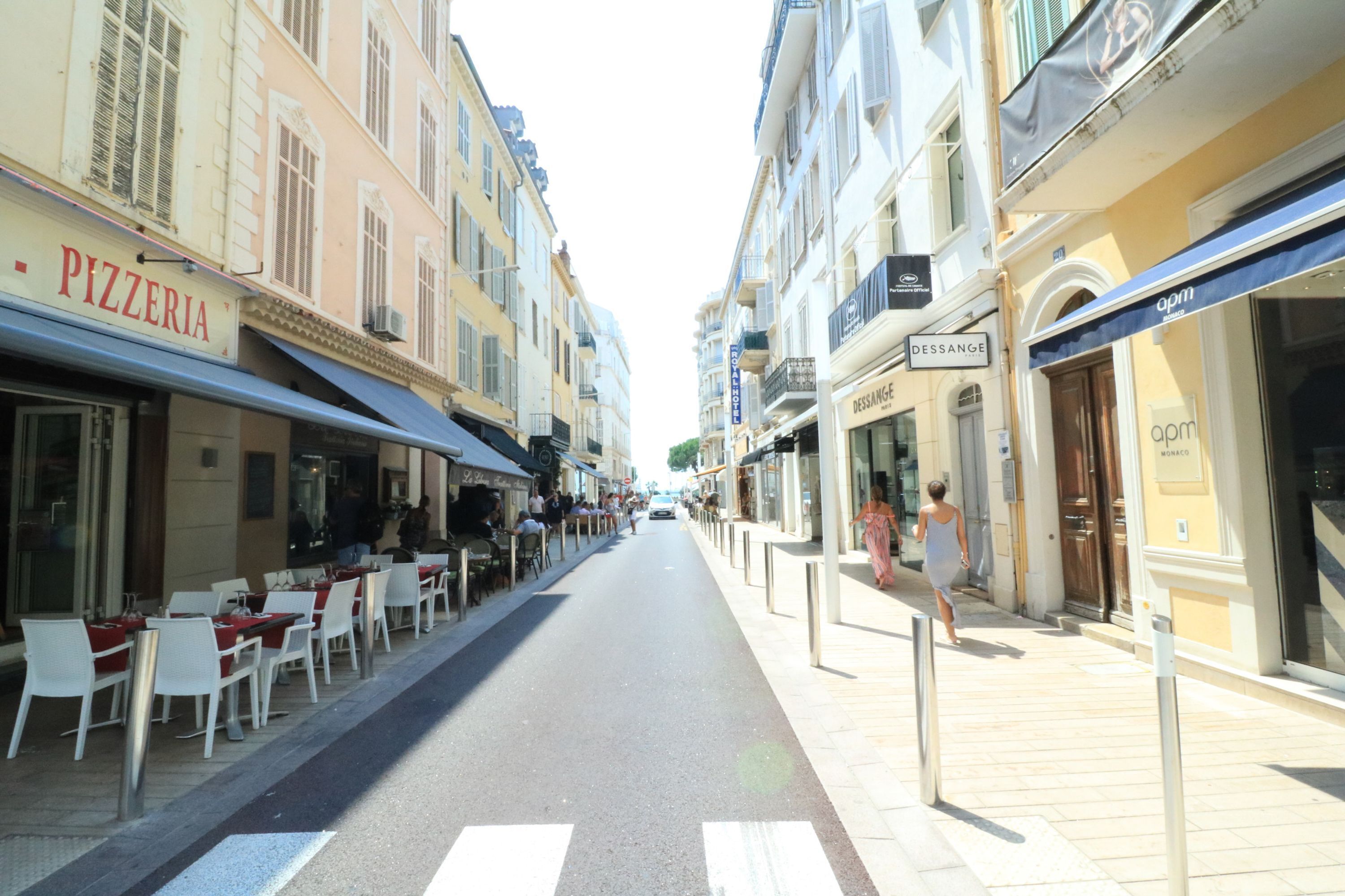 A street with outdoor seating, a pizzeria, and a boutique store.