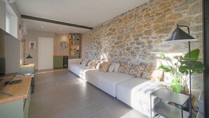A modern living room with a stone wall, a sofa, and a small table with a lamp. - 3 Chambres Terrasse et 1 Chambre Studio A4b026 (Cannes)