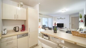Una cucina moderna con lavastoviglie, macchina del caffè e una bottiglia di vino sul bancone.