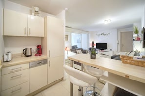 A modern kitchen with a dishwasher, a coffee maker, and a wine bottle on the counter. - Moderne 2 Pi ces Avec Terrasse A1b263 (Cannes)