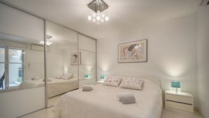 Una camera da letto moderna con un letto grande, uno specchio, un comodino e un'opera d'arte appesa al muro.