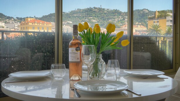 A table set for two with a bottle of wine, a vase with yellow flowers, and clear glasses. - Ref 670723 in Cannes (Cannes)