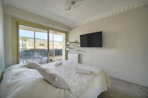 Ein Hotelzimmer mit einem großen Bett, einem an der Wand befestigten Fernseher und Blick auf die Stadt durch das Fenster.