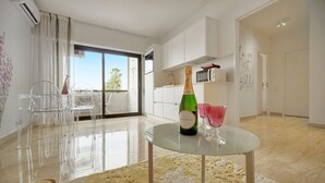 Ein modernes Wohnzimmer mit einem Glastisch, einer Champagnerflasche und einem rosafarbenen Glas.