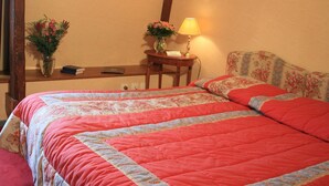 Une chambre à coucher avec un grand lit, une table de chevet avec une lampe, un tableau encadré au mur et un lustre.