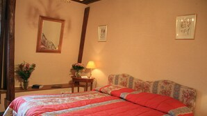 Une chambre avec un grand lit, une table de chevet avec une lampe et un miroir au mur.