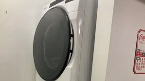 Eine gestapelte Waschmaschine und ein Trockner in einem Raum, an der Wand hängt ein Kalender.