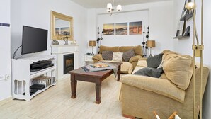 Ein Wohnzimmer mit Fernseher, Kamin, Sofa und Couchtisch.