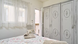 Ein Schlafzimmer mit einem Bett, einem Kleiderschrank und einem Fenster mit durchsichtigen Vorhängen.