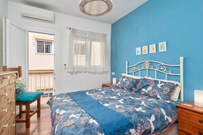 A bedroom with a bed, a wooden dresser, a chair, a nightstand, and a window with a view. - Holiday Home 'De Tio' with Private Terrace, Wi-Fi and Air Conditioning (Torre del Mar)