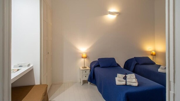 A hotel room with two beds, a small desk, and bedside lamps.