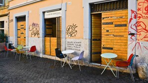 A building with numbered doors, graffiti, and outdoor seating with chairs and tables.