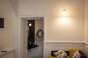 Une chambre comprenant un lit, une table de chevet, une lampe fixée au mur et une porte donnant sur une salle de bain.