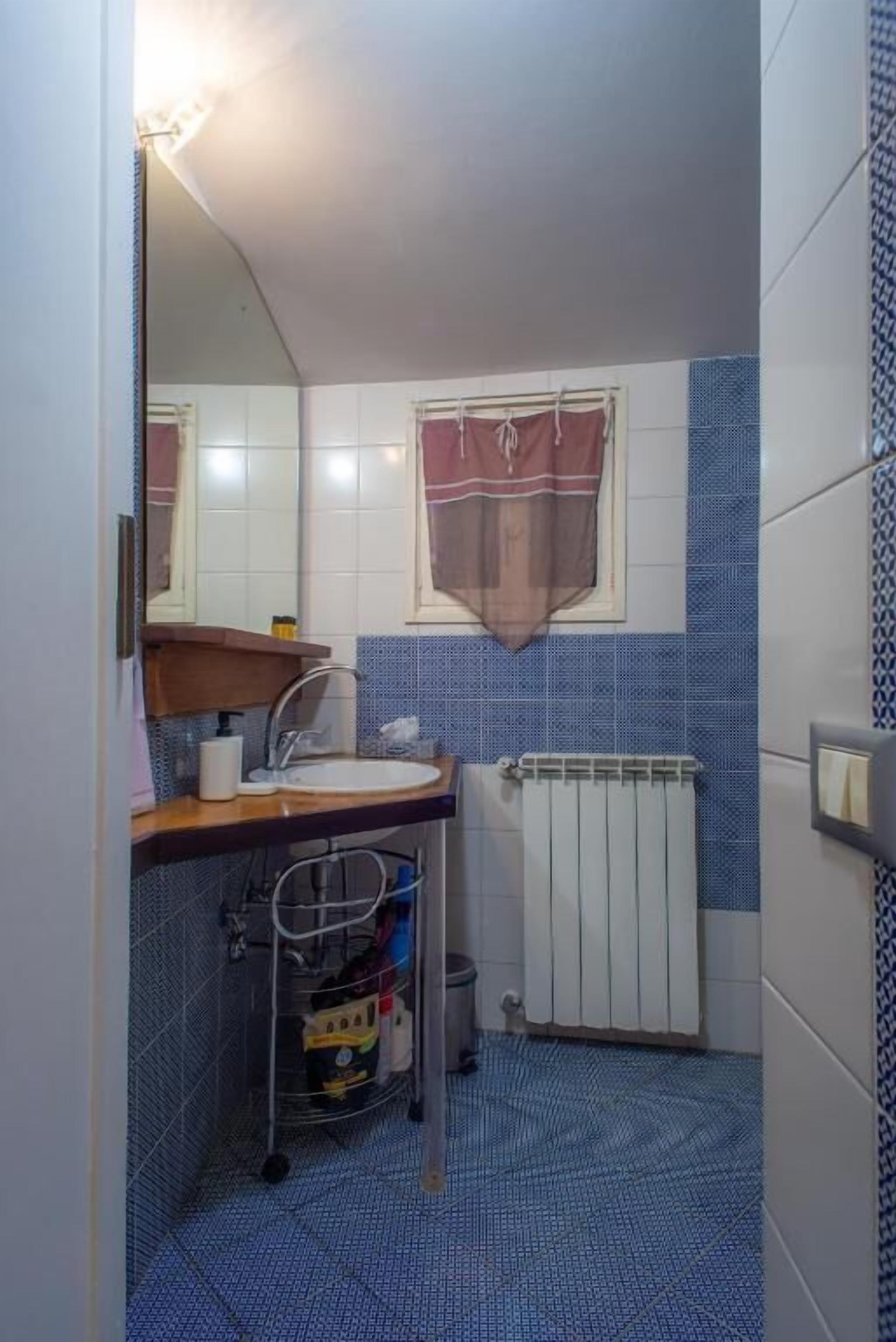 A small bathroom with a sink, mirror, towel rack, and a radiator.