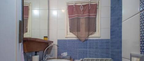 A small bathroom with a sink, mirror, towel rack, and a radiator.