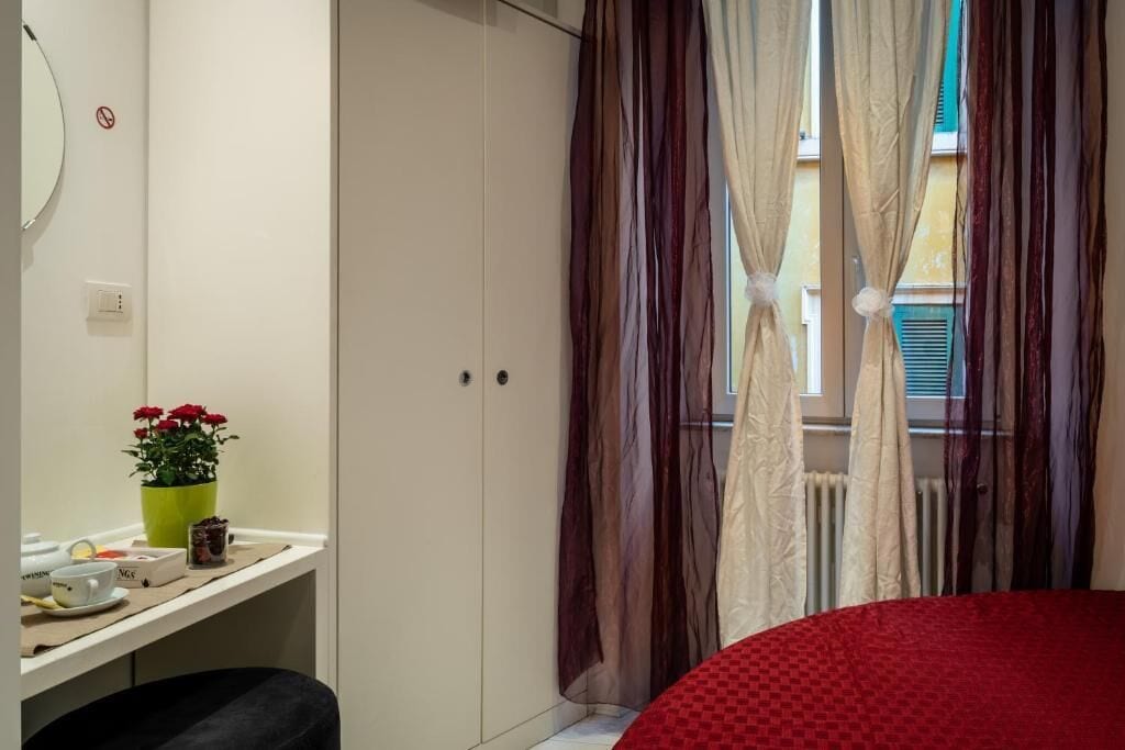 A bedroom with a bed, a desk with a plant, and a wardrobe.