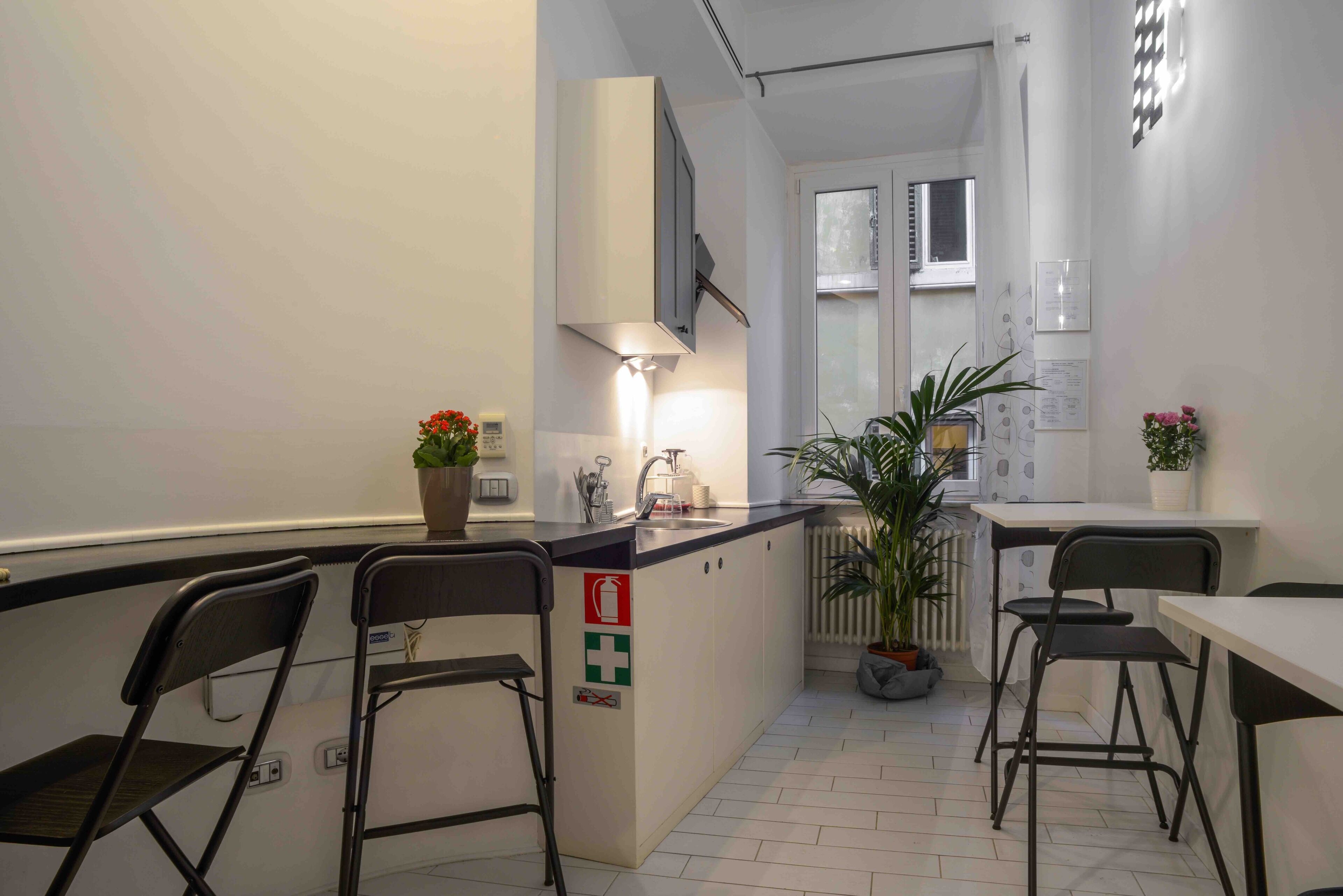 Una cocina moderna con una isla central, taburetes de bar y plantas en macetas.