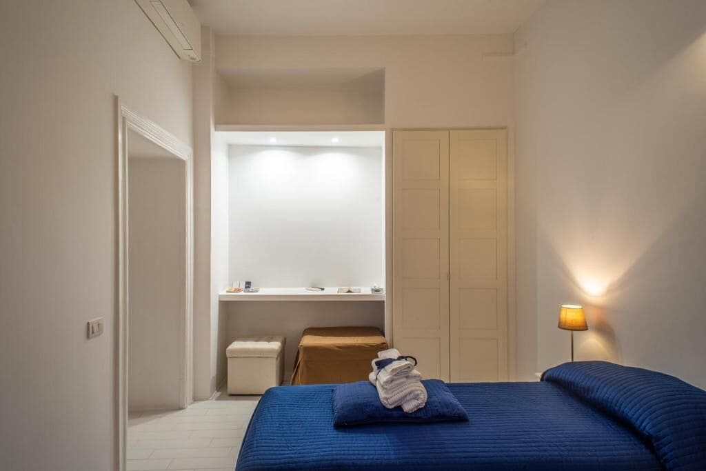 A bedroom with a bed, a nightstand, a mirror, and a wardrobe.