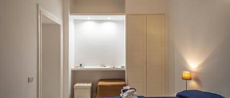 A bedroom with a bed, a nightstand, a mirror, and a wardrobe.