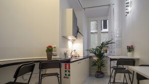 A modern kitchen with a central island, bar stools, and a potted plant.