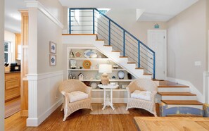 A staircase with blue railings, a white door, and a shelf with decorative items. - Son Worshipers - Seaside Home near Iconic Town Council! (Santa Rosa Beach)
