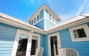 A corner of a building with a blue exterior, white trim, and a small tower-like structure. - Son Worshipers - Seaside Home near Iconic Town Council! (Santa Rosa Beach)