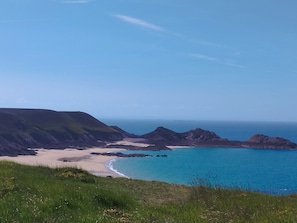 Et kystlandskab med strand, græsarealer og klippeformationer.