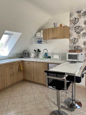 Una cocina moderna con armarios de madera, una encimera con varios electrodomésticos, una ventana y vistas al exterior.