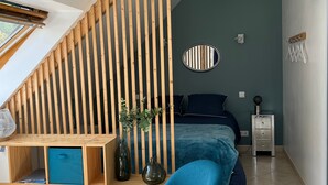 Ett modernt sovrum med ett sluttande tak, en säng, ett skrivbord med förvaringsutrymme, en stol, en tv och ett nattduksbord.