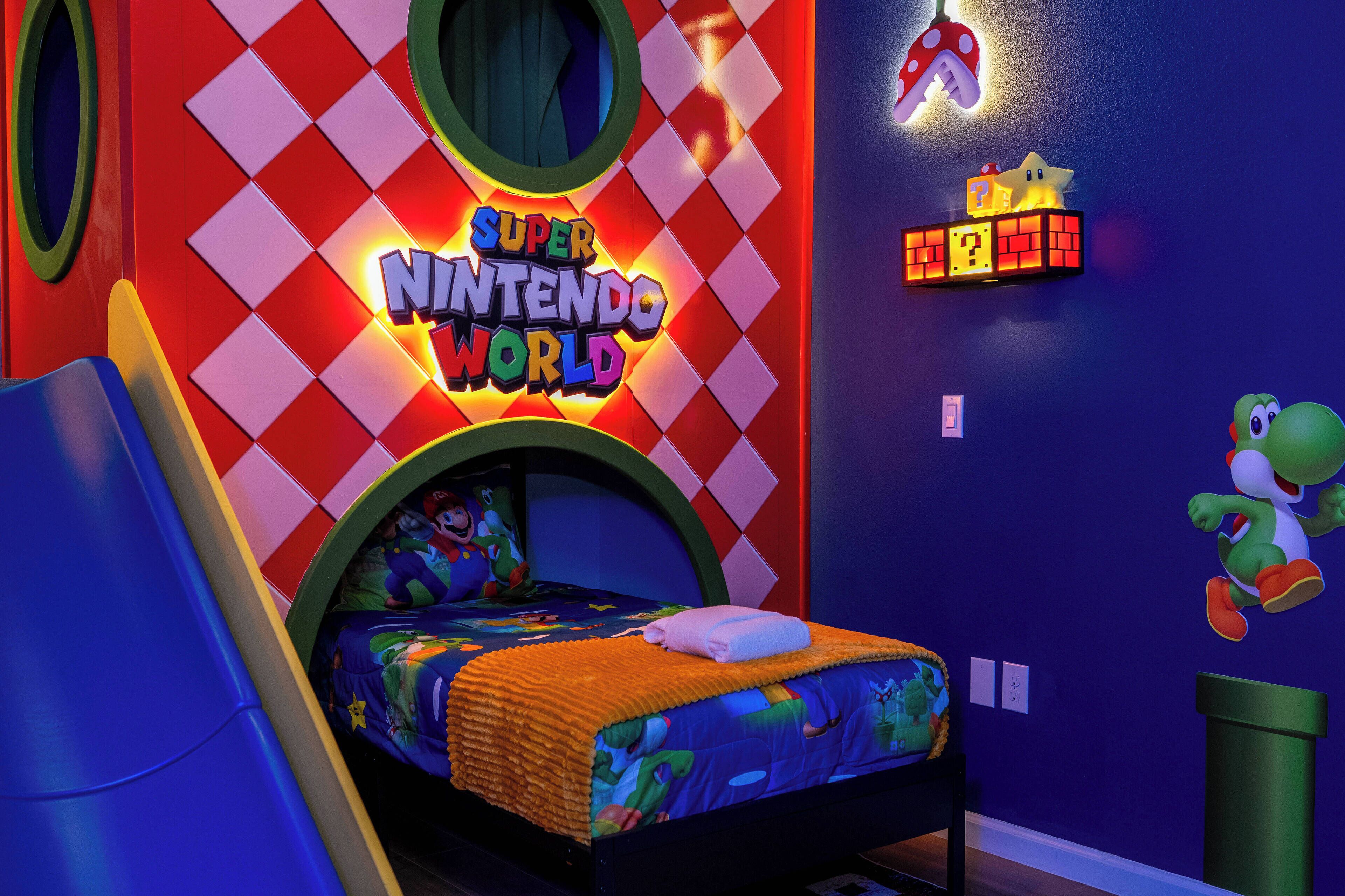 A Super Nintendo World themed room with a bed, a slide, and various decorations including a mushroom lamp and Mario character.