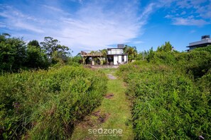 A modern house with a pathway leading to it, surrounded by lush greenery. - House w/ BBQ and Lake Access Mat0021 (Garopaba)
