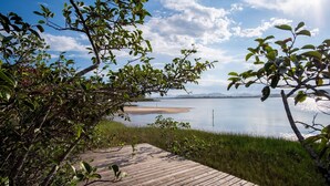 Ett trädäck som leder fram till en lugn sjö med klar himmel.