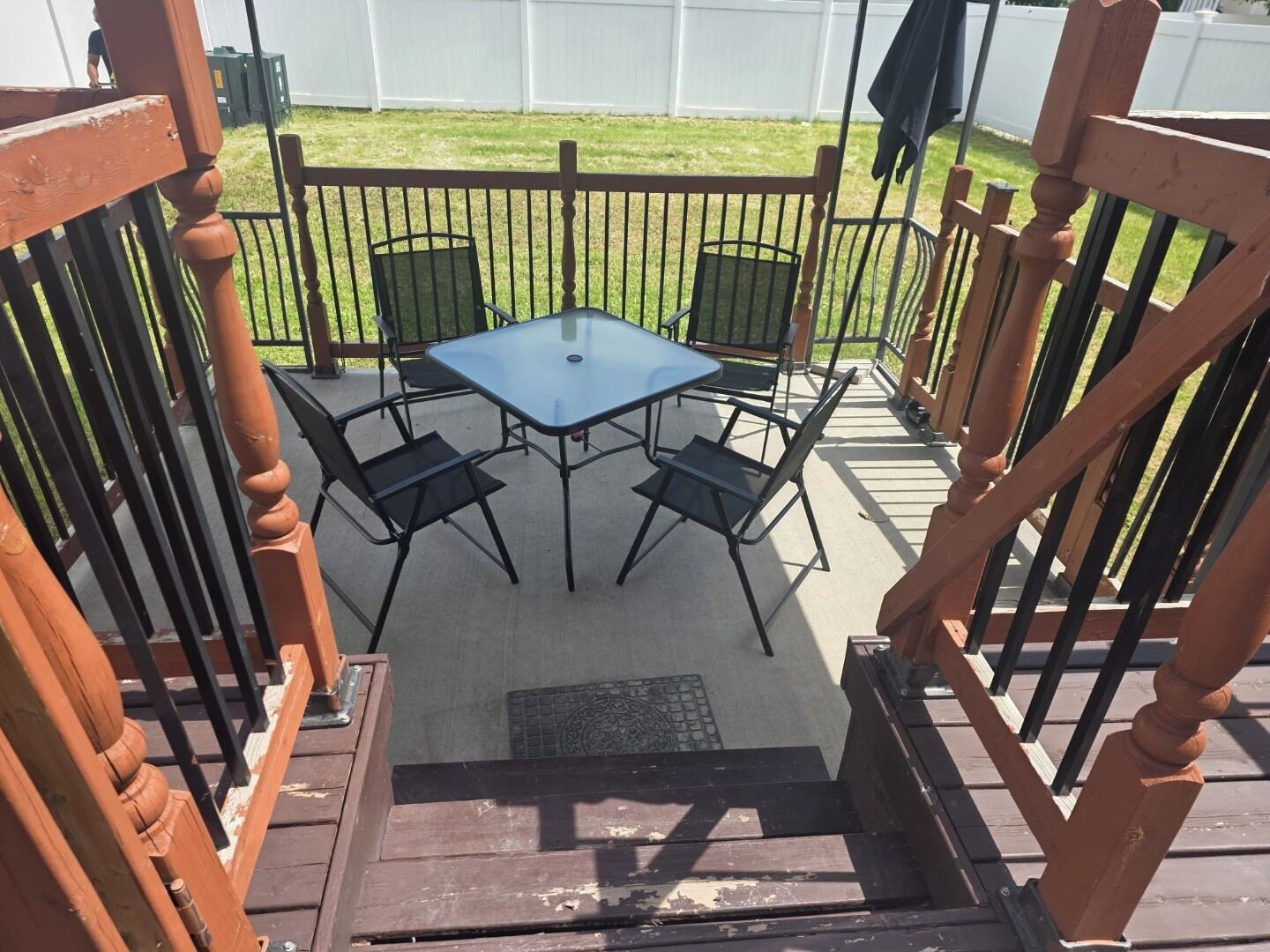 Un espace extérieur aménagé avec une table et des chaises, une terrasse en bois et une clôture en métal.