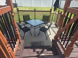 Un espace extérieur aménagé avec une table et des chaises, une terrasse en bois et une clôture en métal.