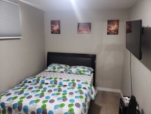 Ein Schlafzimmer mit einem Bett, einem Fernseher und drei Bildern an der Wand.