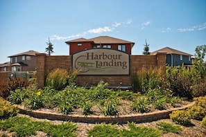 Une enseigne indiquant « Harbour Landing », avec un mur en briques et un jardin aménagé devant.