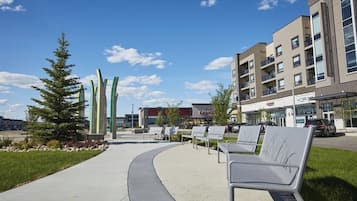A modern building with a curved walkway, outdoor seating, and a clear sky.