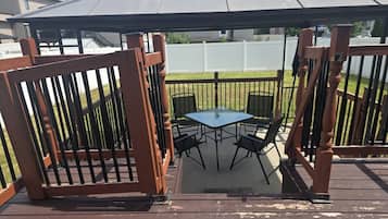 Un patio cubierto con una mesa y sillas, rodeado por una valla de madera.