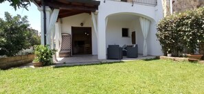 Una casa con patio coperto, un piccolo giardino e un ingresso che conduce all'interno.