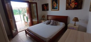 Una camera da letto con un letto, due lampade da comodino, un comodino e una porta che dà su un balcone.