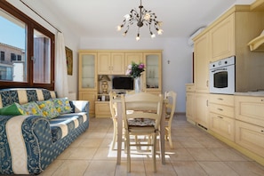 Un espace de vie chaleureux comprenant un canapé, une table à manger, des chaises, un téléviseur et un coin cuisine avec des placards et un four.